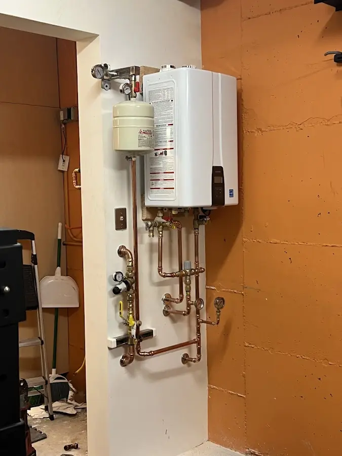 Plumbing technician inspecting water heater connections in New Prague